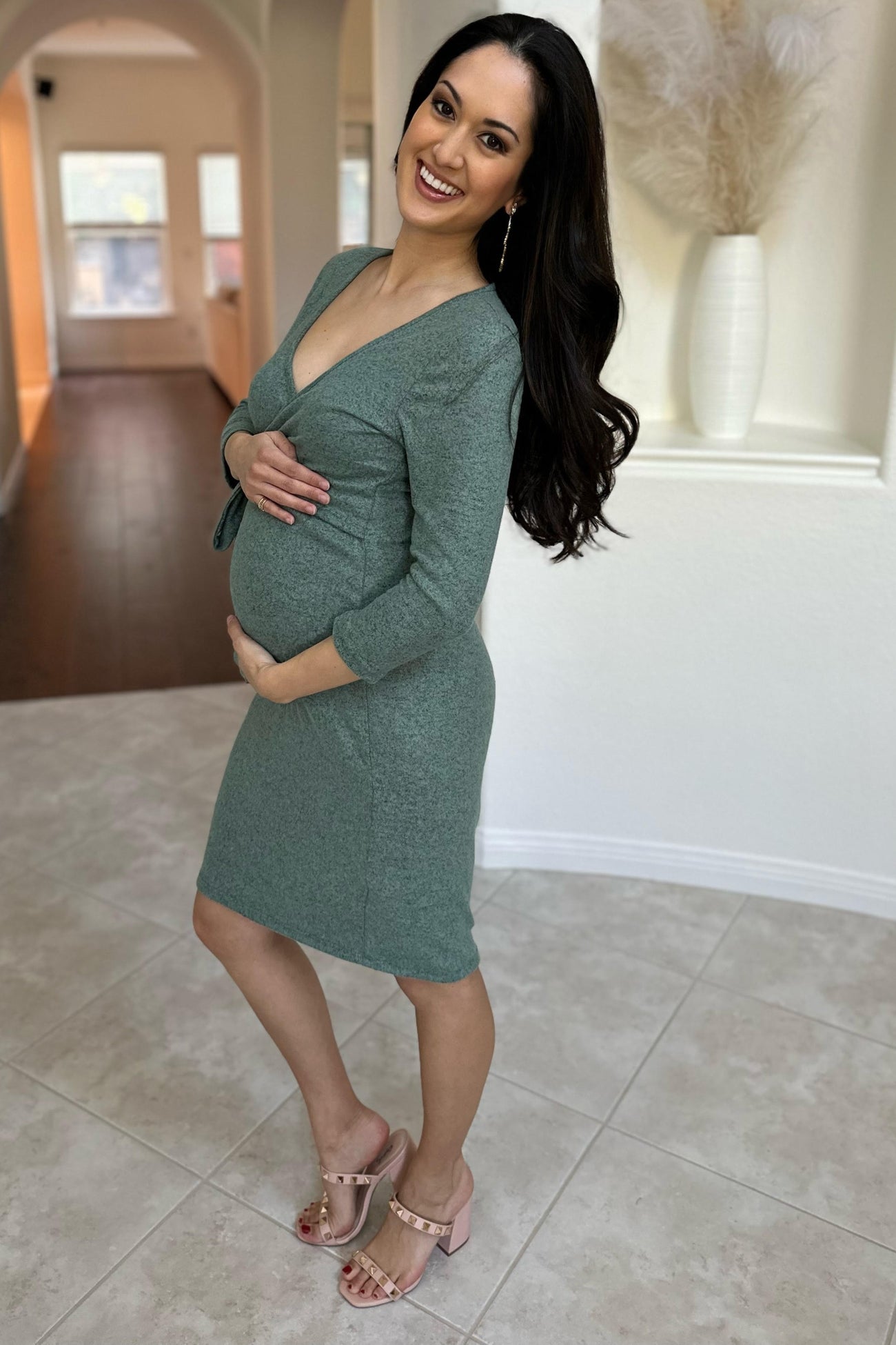 woman wearing a green short sleeve maternity dress and holding her baby bump