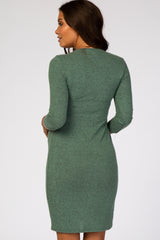 Back view of a woman wearing a sage green long sleeve fitted maternity dress