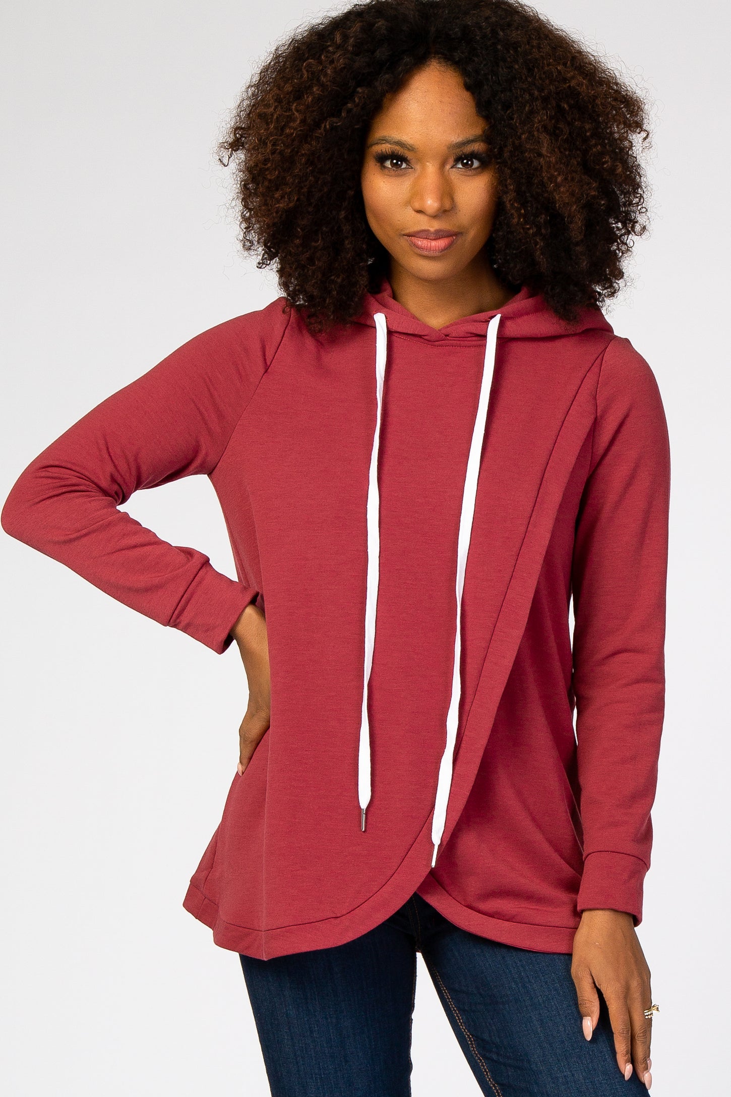 woman wearing a maroon long sleeve hooded sweatshirt with a diagonal hem and white drawstrings