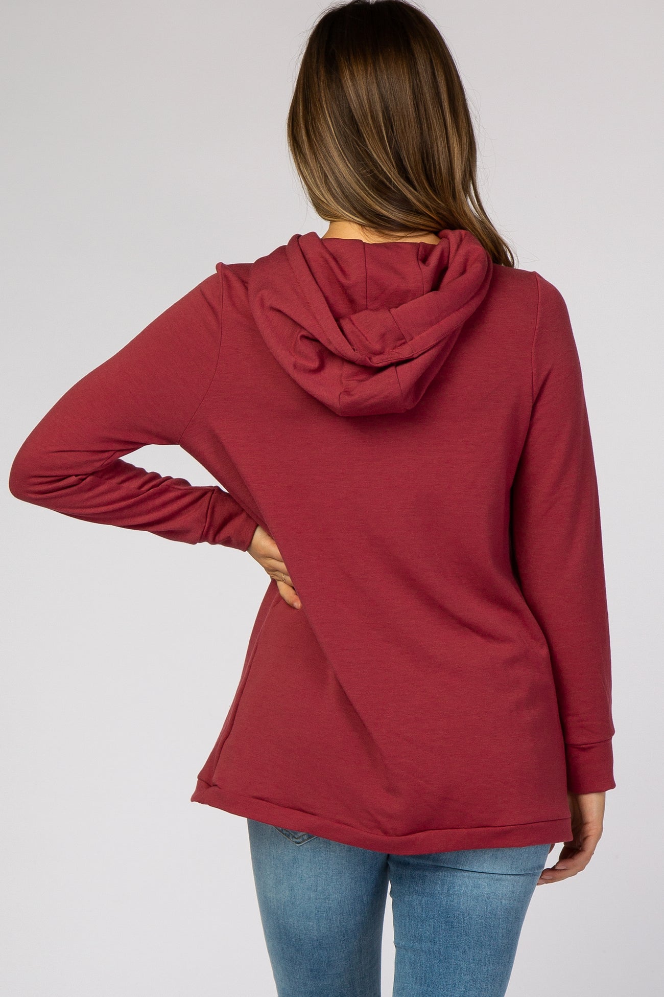 woman wearing a rust red maternity pullover hoodie with a hood, shown from the back