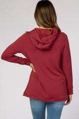 woman wearing a rust red maternity pullover hoodie with a hood, shown from the back