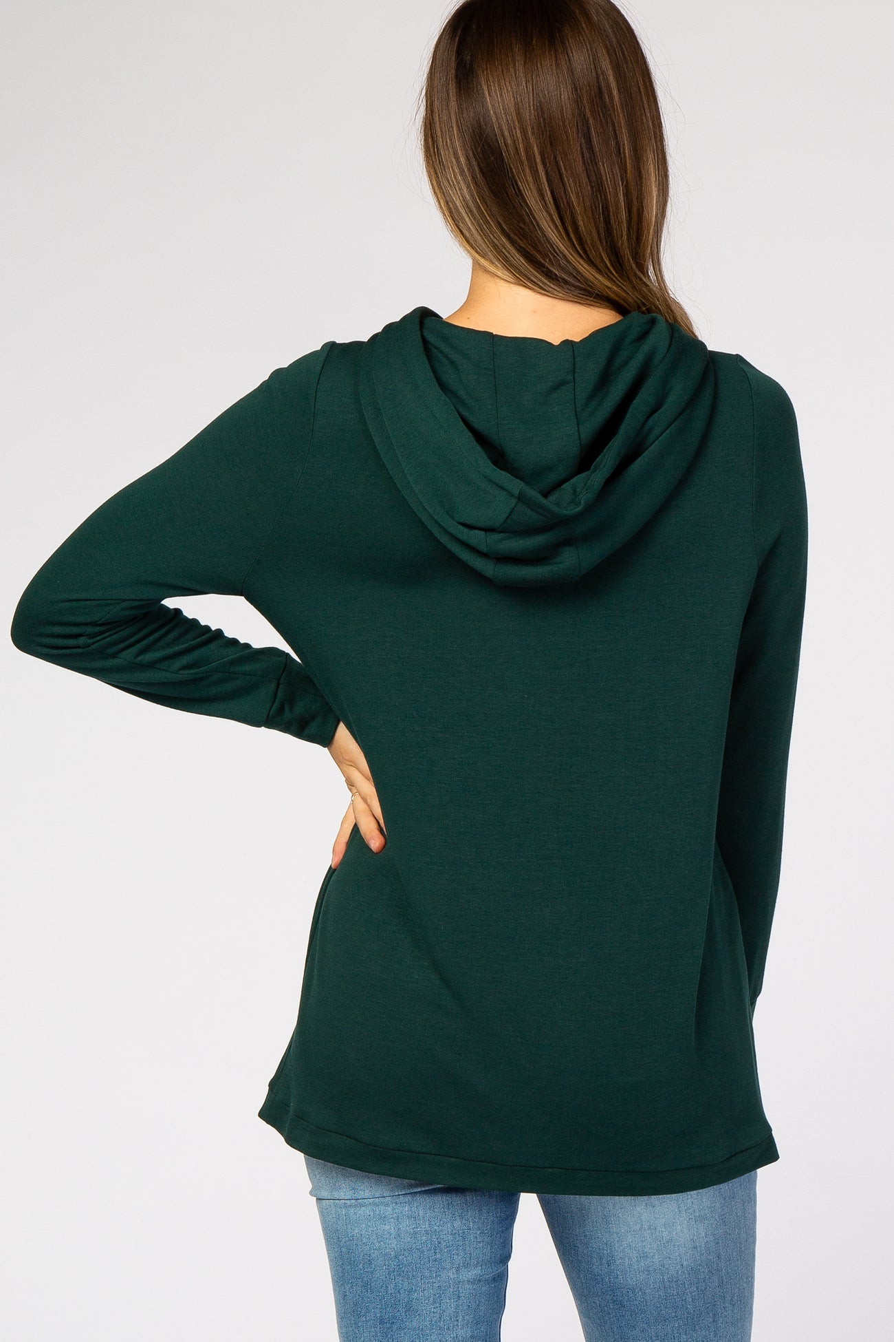 woman wearing a dark green maternity hoodie from the back, features a hood and long sleeves, paired with blue jeans