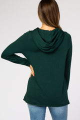 woman wearing a dark green maternity hoodie from the back, features a hood and long sleeves, paired with blue jeans