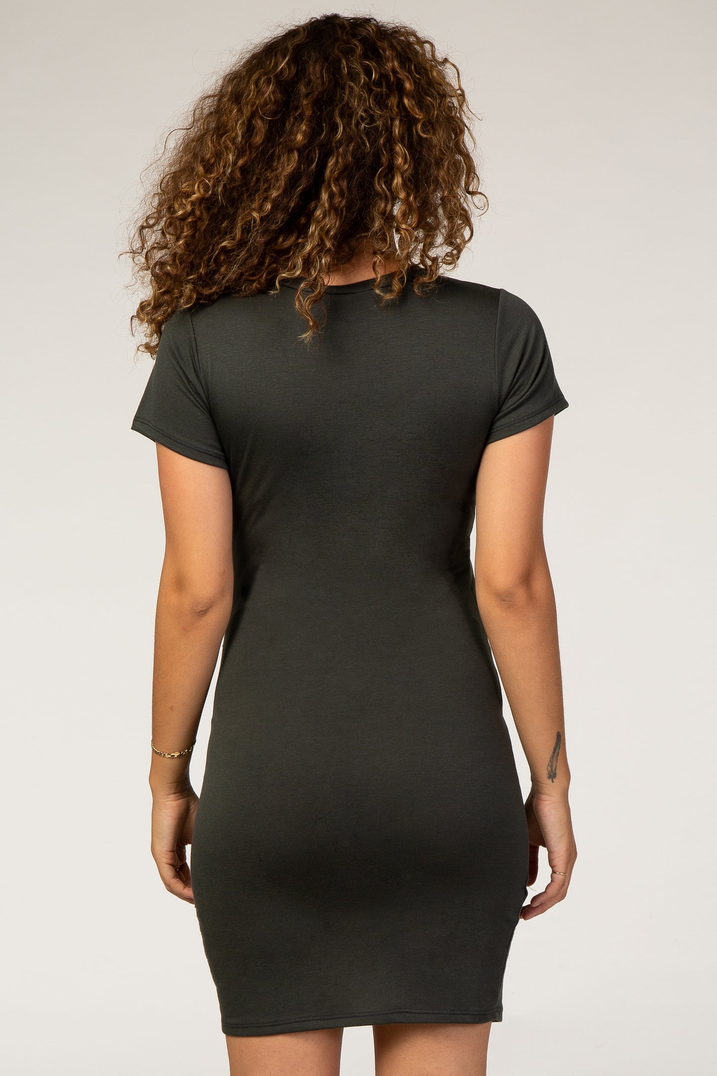 woman wearing a dark green fitted maternity dress, shown from the back