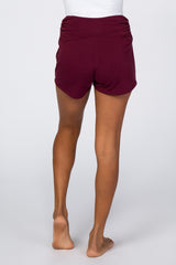 woman wearing maroon high-waisted shorts, seen from the back, with a flowing design and a comfortable fit