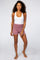 woman wearing white ribbed tank top and mauve high waisted lounge shorts against white background