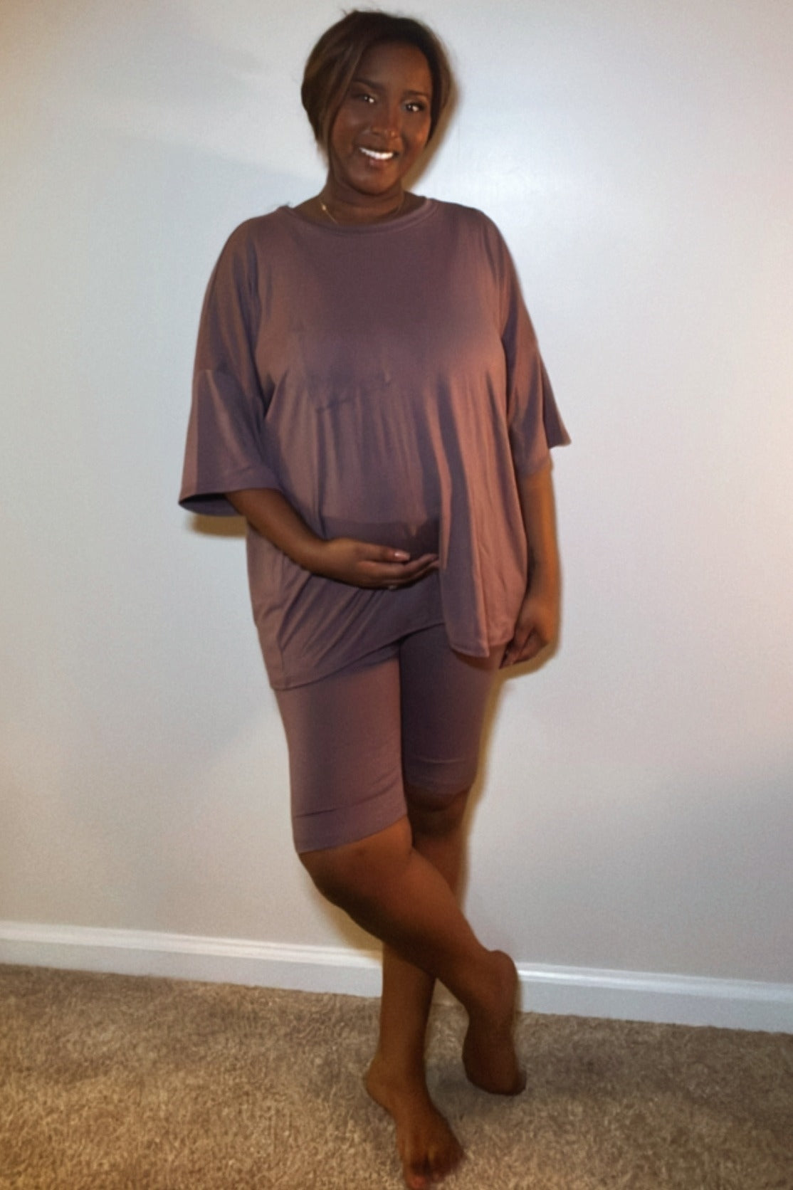 woman wearing a brown maternity short sleeve top and matching shorts, holding her baby bump