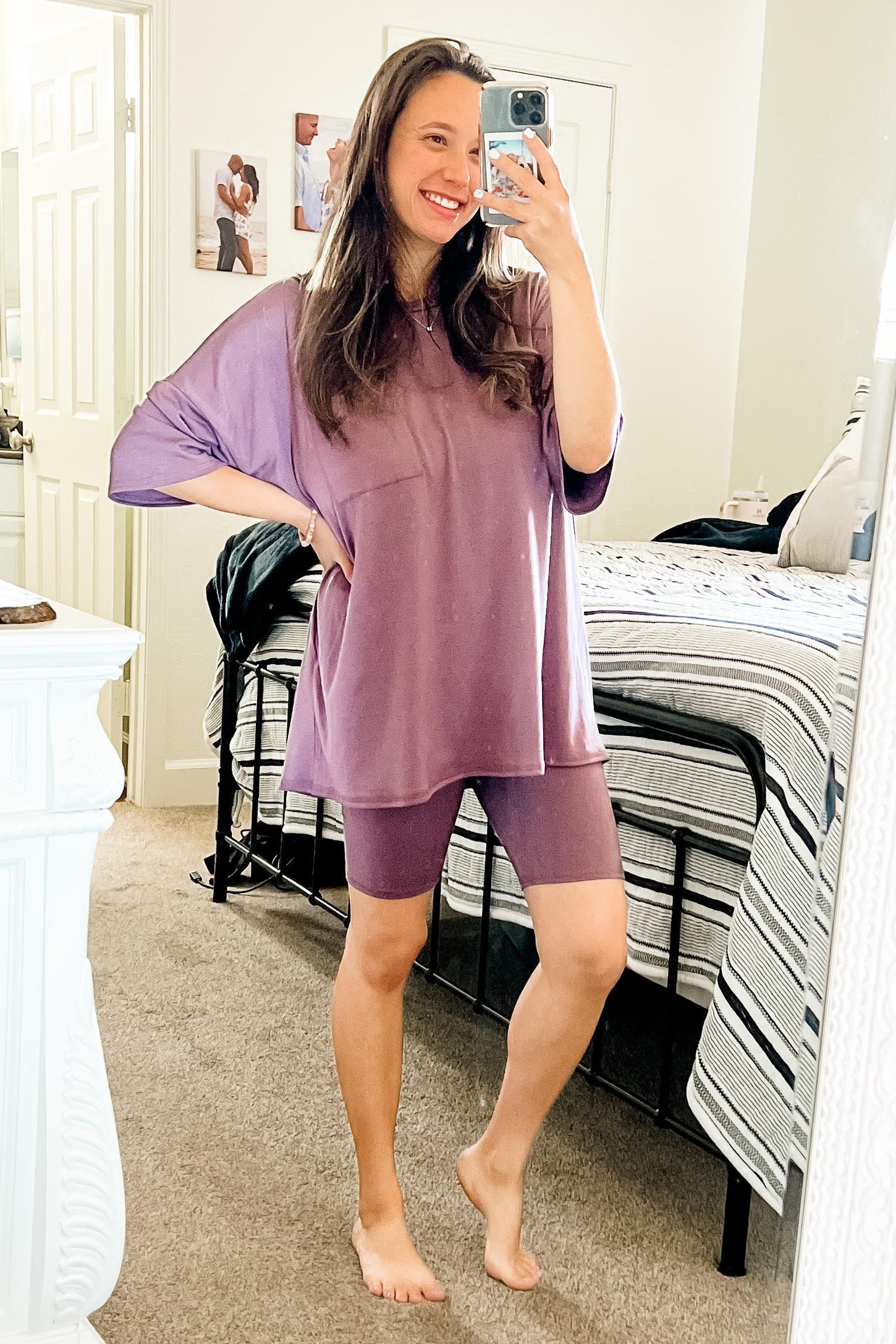 woman wearing a loose purple oversized top and matching purple bike shorts, posing in front of a mirror