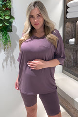 woman wearing a mauve maternity t-shirt with pocket and matching bike shorts, showing her baby bump