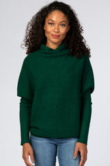 woman wearing a dark green oversized sweater with a cowl neck and long sleeves, paired with blue jeans