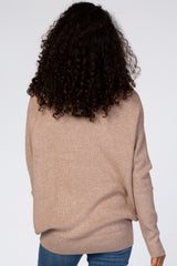 Back view of a woman with curly dark hair wearing a tan ribbed knit sweater and blue jeans