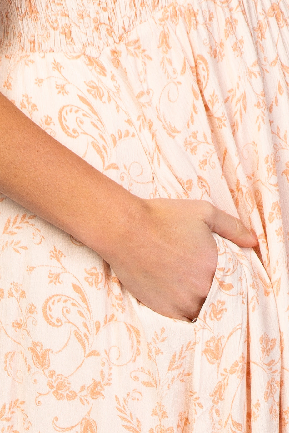 light pink maternity dress with floral print and a pocket, being held by a hand