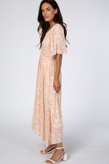 woman wearing a peach floral maxi dress with flutter sleeves and smocked bodice, standing sideways against a white background