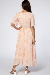 woman wearing a peach floral smocked maxi dress with short sleeves and open back