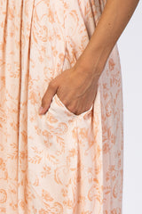 close-up of a woman’s hand in the pocket of a light peach floral print maxi dress with textured fabric