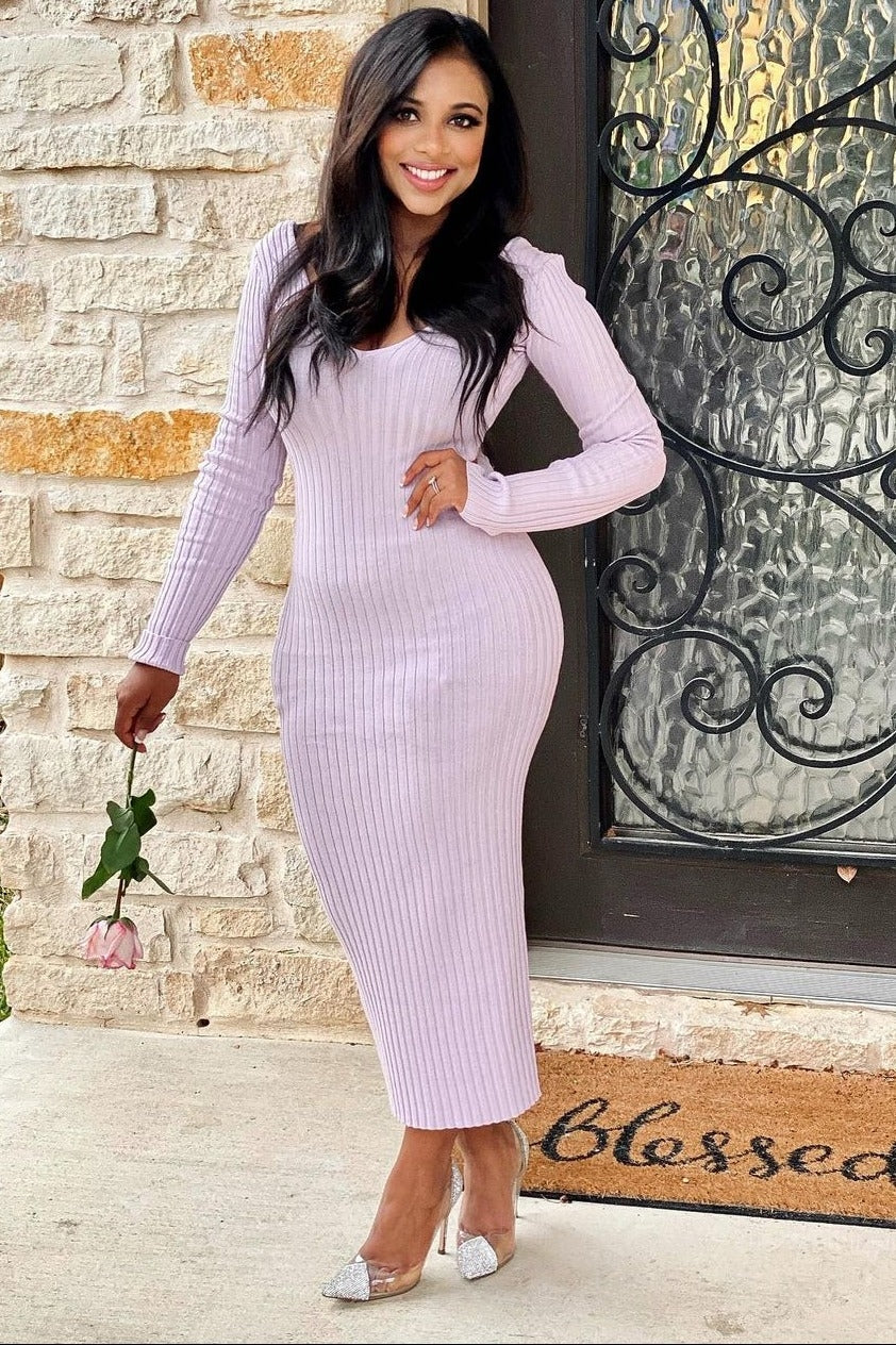 woman wearing a light pink ribbed bodycon dress with long sleeves and holding a rose