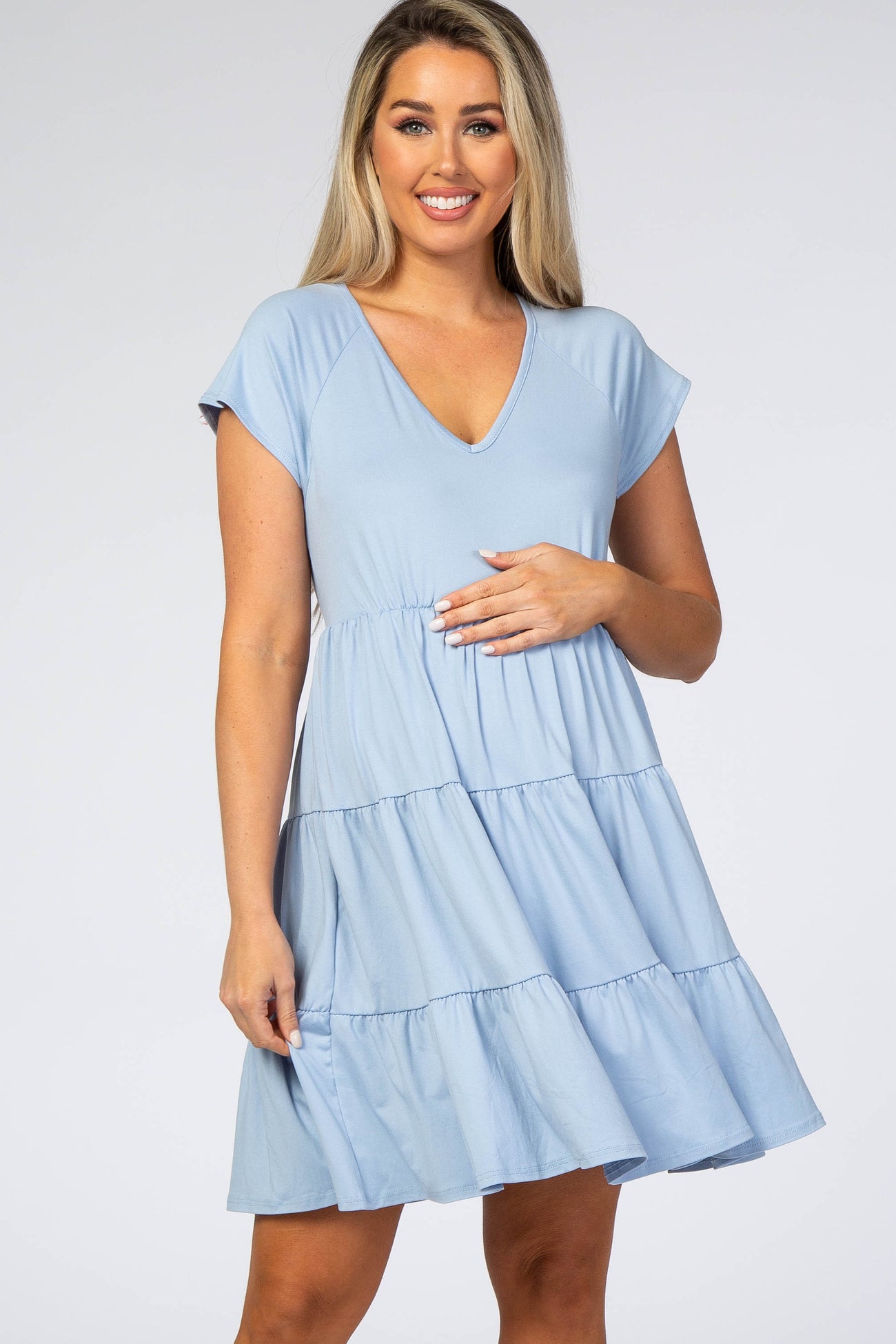 smiling pregnant woman wearing a light blue v-neck tiered maternity dress