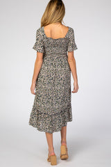 woman wearing a black floral maternity dress with short sleeves and a ruffled hem, showing a baby bump