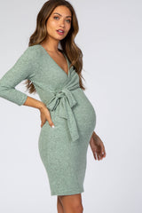 woman wearing a green long sleeve maternity dress with a tie detail and a visible baby bump