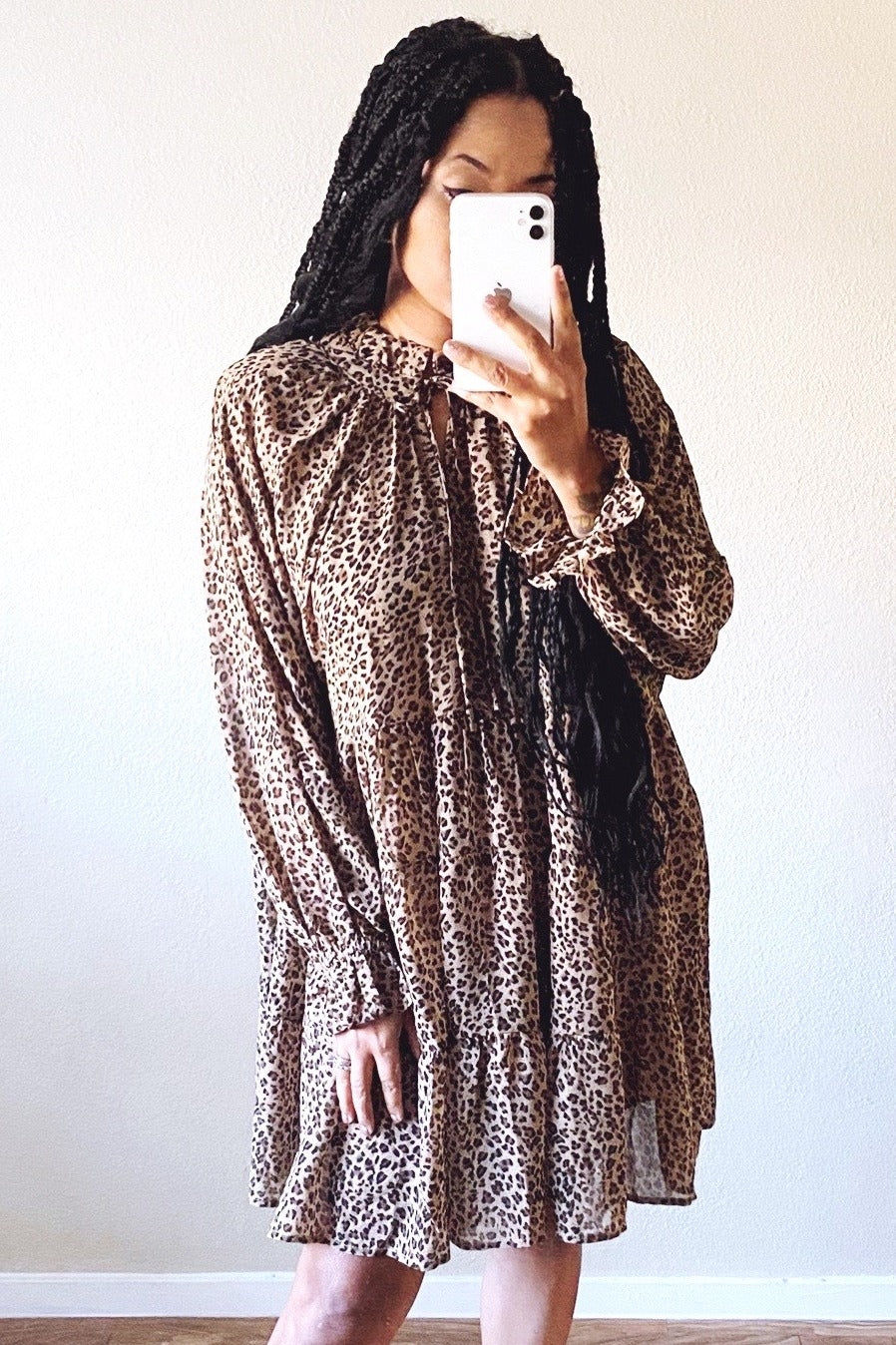 woman wearing a leopard print long sleeve dress with a ruffled hem and high neck detail