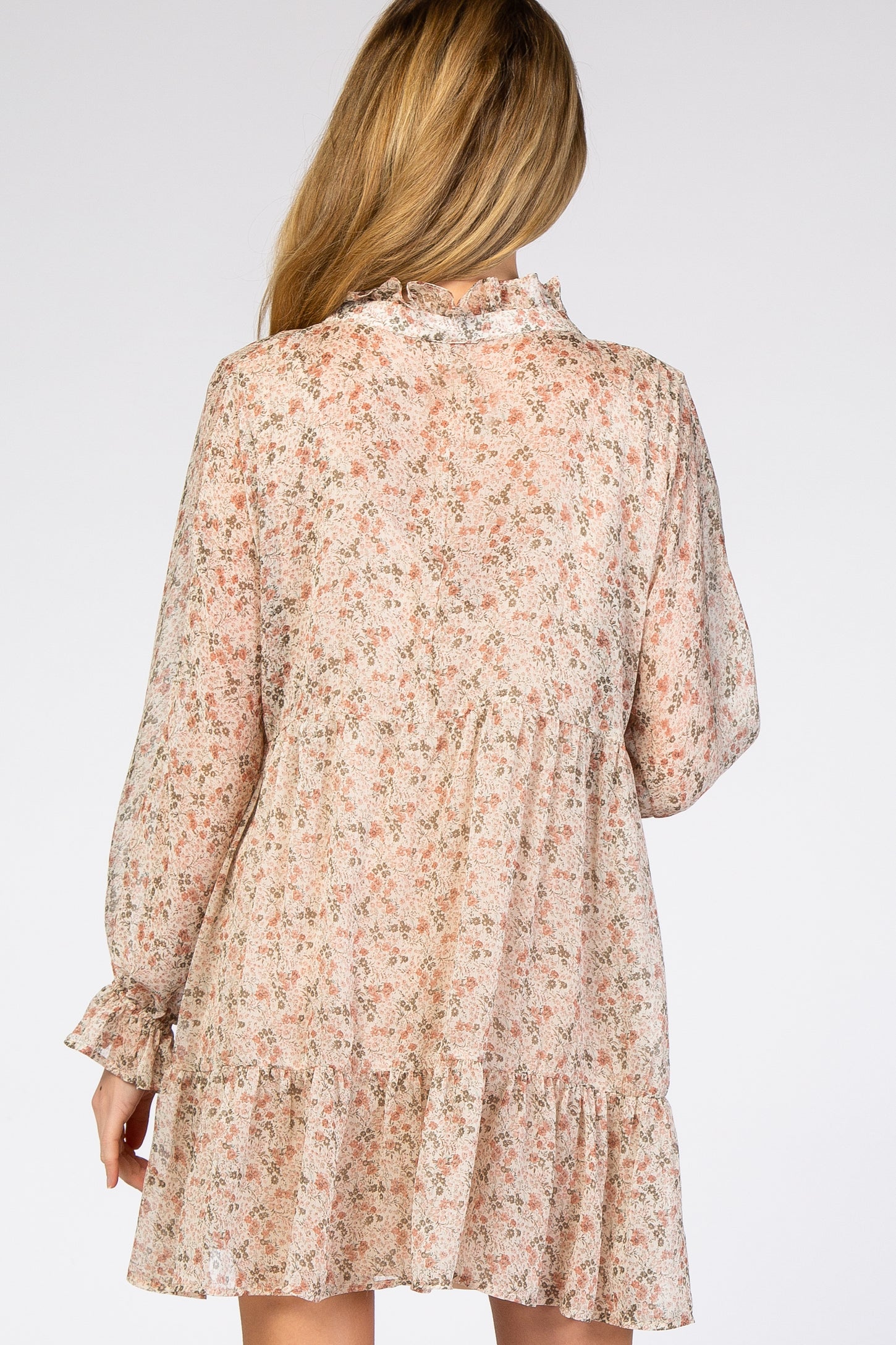 woman wearing a floral print long sleeve maternity dress with a tiered hem and ruffle detailing, showing a baby bump