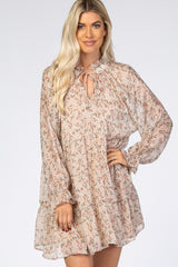 woman wearing a flowy floral print long sleeve dress with a tie neckline and ruffled hem