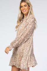 woman wearing a floral long sleeve mini dress with ruffled hem and tie neck detail