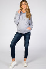 pregnant woman wearing a grey maternity hoodie and dark wash distressed skinny jeans with white sneakers