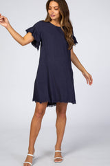 woman wearing a navy blue linen shift dress with frayed ruffle sleeves and hemline