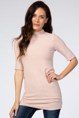 woman wearing a light pink short sleeve mock neck tunic top paired with jeans