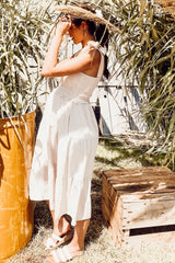 woman wearing a white maternity sundress with a smocked bodice and tiered skirt, standing outdoors with a baby bump visible