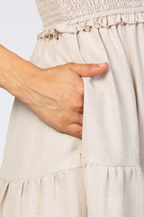 close-up of a woman's hand in the pocket of a light beige smocked dress with ruffle details