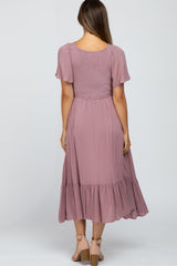Back view of a woman wearing a mauve smocked midi dress with flutter sleeves and a tiered hem
