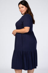 Plus size woman wearing a navy blue short sleeve tiered midi dress against a white background