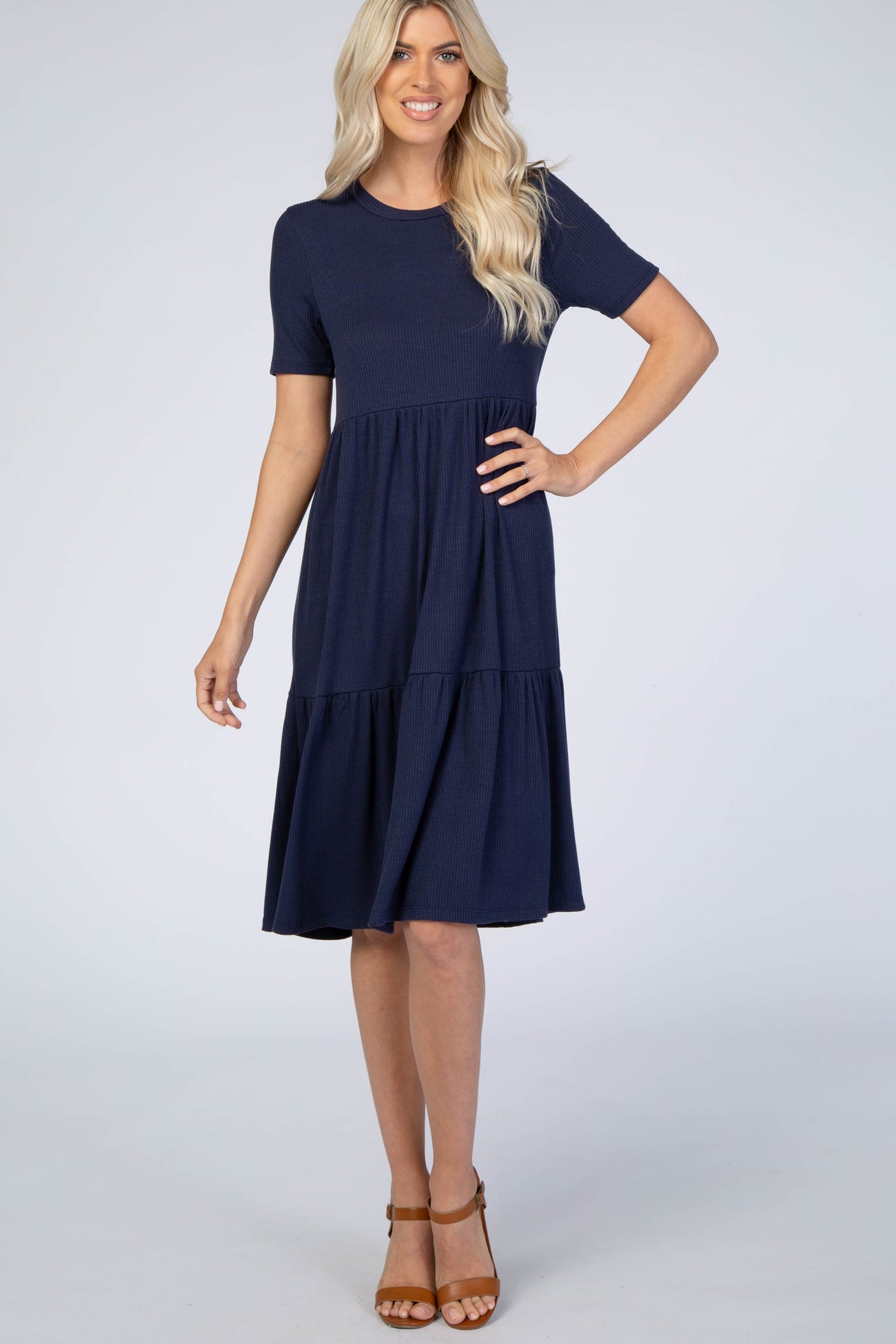 woman wearing a navy blue short sleeve tiered dress with a fitted top and flared bottom