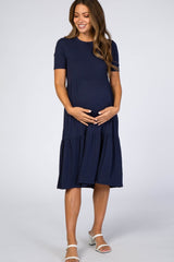 woman wearing a navy blue short sleeve maternity dress with a tiered skirt and visible baby bump