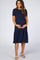 woman wearing a navy blue short sleeve maternity dress with a tiered skirt and visible baby bump