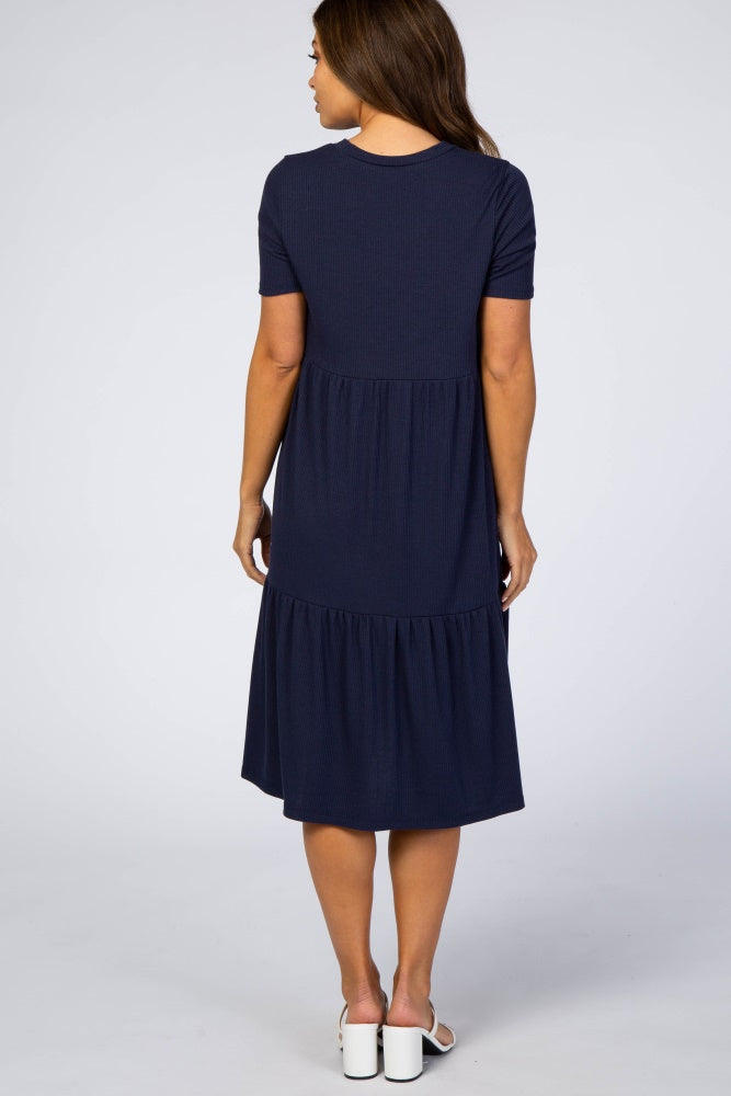 woman wearing a navy blue short sleeve maternity dress with a tiered skirt, showing the back view
