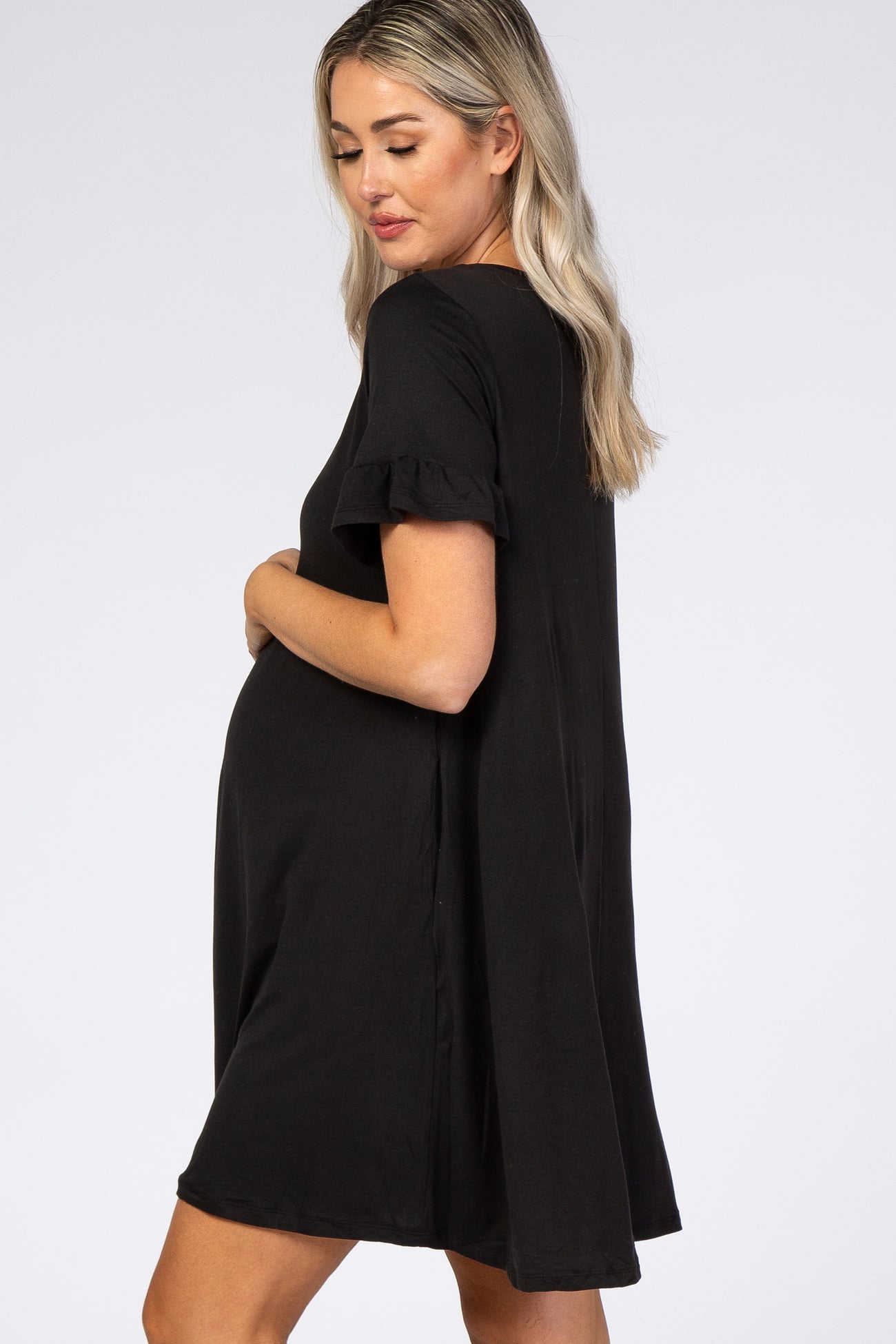 woman wearing a black maternity dress with ruffled short sleeves and a visible baby bump