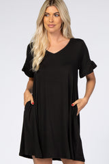 woman wearing a black short sleeve dress with a v-neck and ruffled sleeves, featuring front pockets