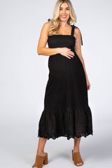 pregnant woman in black eyelet maternity midi dress with tie straps and smocked bodice