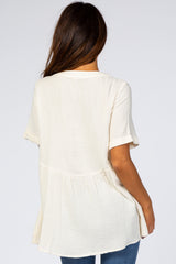 back view of woman wearing cream short sleeve babydoll top with textured fabric and cuffed sleeves