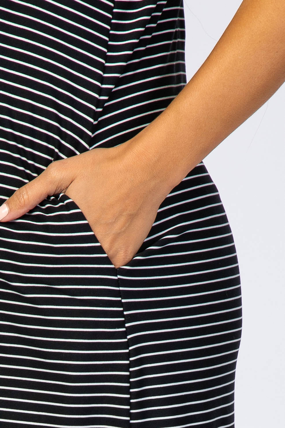 close up of a person's hand in the side pocket of a black and white striped dress