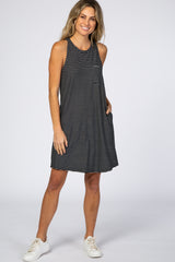 woman wearing a black and white striped sleeveless maternity dress with pockets and white sneakers