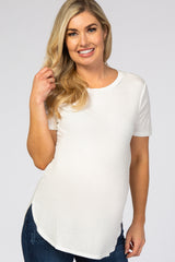 smiling pregnant woman wearing a white short sleeve ribbed maternity top and blue jeans