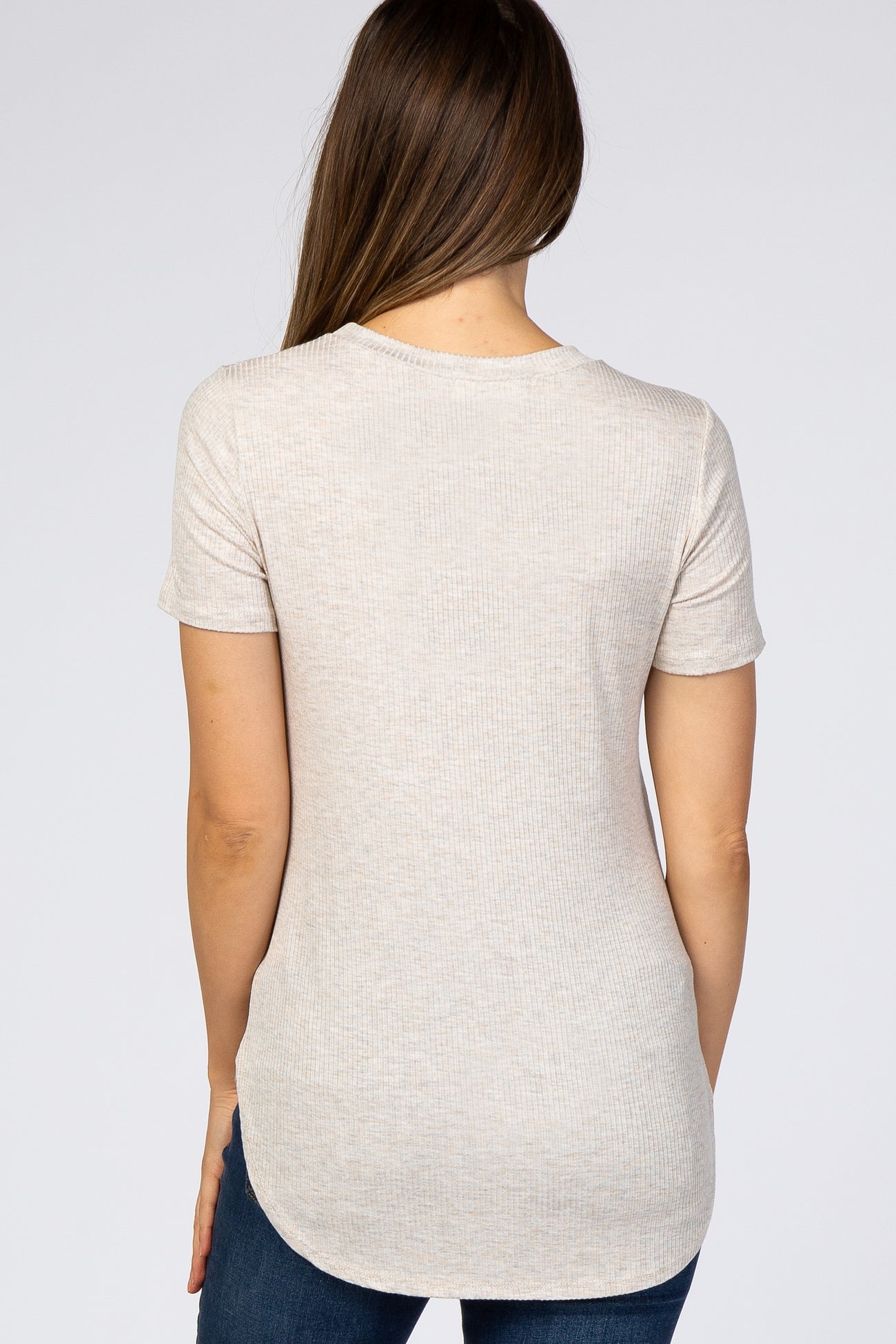 woman wearing a light beige short sleeve maternity top with a rounded hem