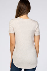 woman wearing a light beige short sleeve maternity top with a rounded hem