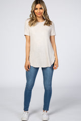 woman wearing a light beige short sleeve top with side slits and blue skinny jeans
