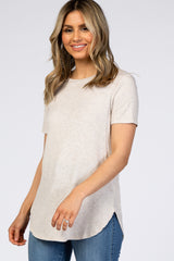 woman wearing a light beige short sleeve top with a subtle texture and rounded hem, smiling in a casual pose
