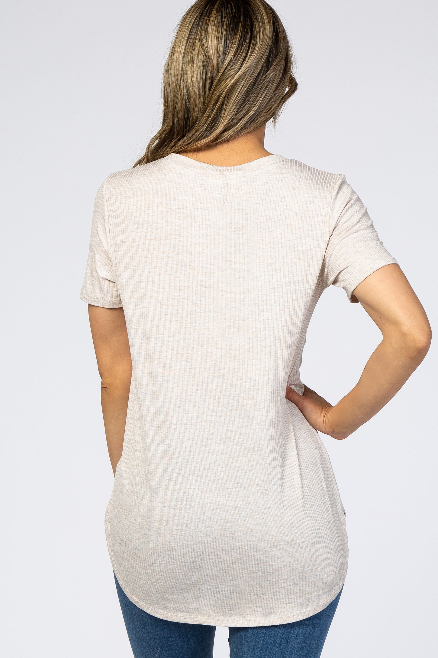 woman wearing a light beige short sleeve top with a relaxed fit and ribbed texture, showing the back view